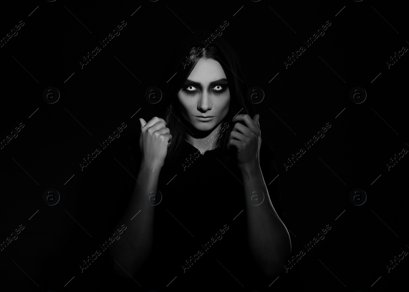 Photo of Mysterious witch with spooky eyes on dark background. Black and white effect