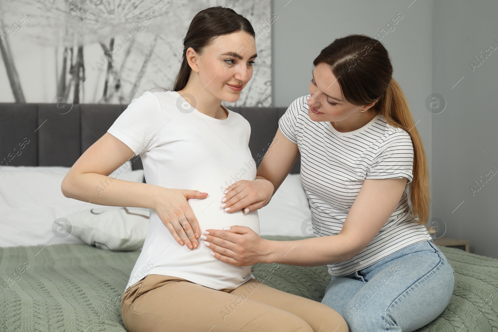 Photo of Doula taking care of pregnant woman in bedroom. Preparation for child birth