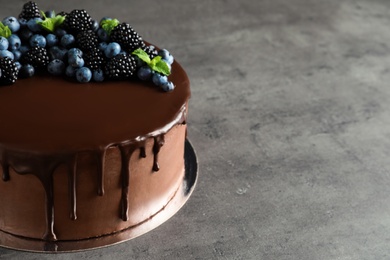 Fresh delicious homemade chocolate cake with berries on gray table. Space for text