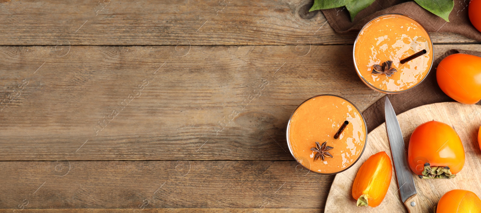 Image of Tasty persimmon smoothie with anise and fresh fruits on wooden table, flat lay with space for text. Banner design