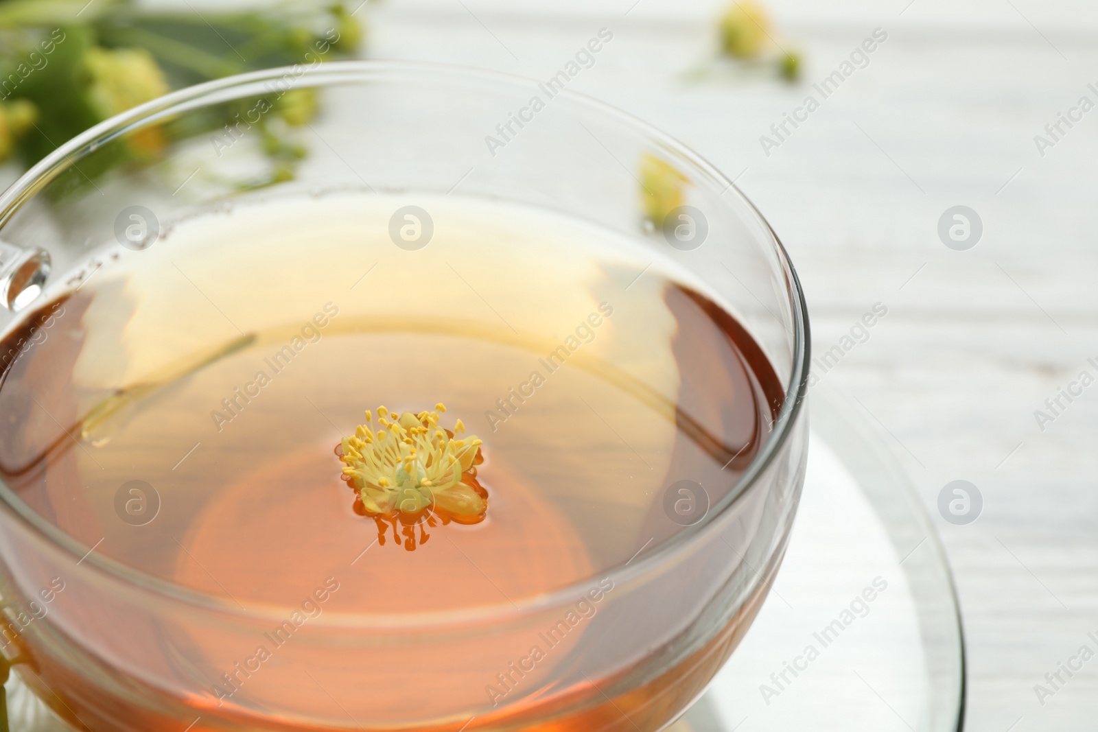 Photo of Cup of tea with linden blossom on table, closeup