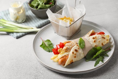 Photo of Delicious pita wrap with sausage, french fries and pepper on light gray table