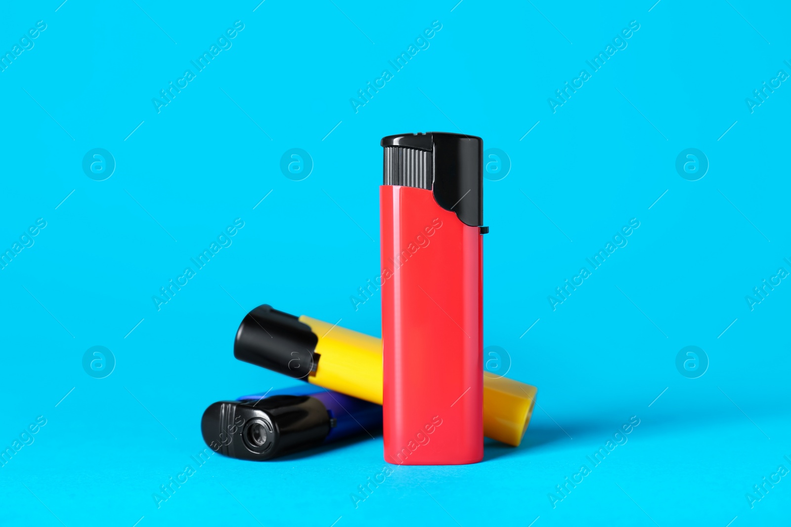 Photo of Different plastic cigarette lighters on light blue background