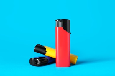 Photo of Different plastic cigarette lighters on light blue background