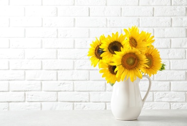 Photo of Jug with beautiful yellow sunflowers on table