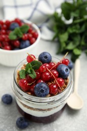 Delicious yogurt parfait with fresh berries and mint on light grey table, closeup