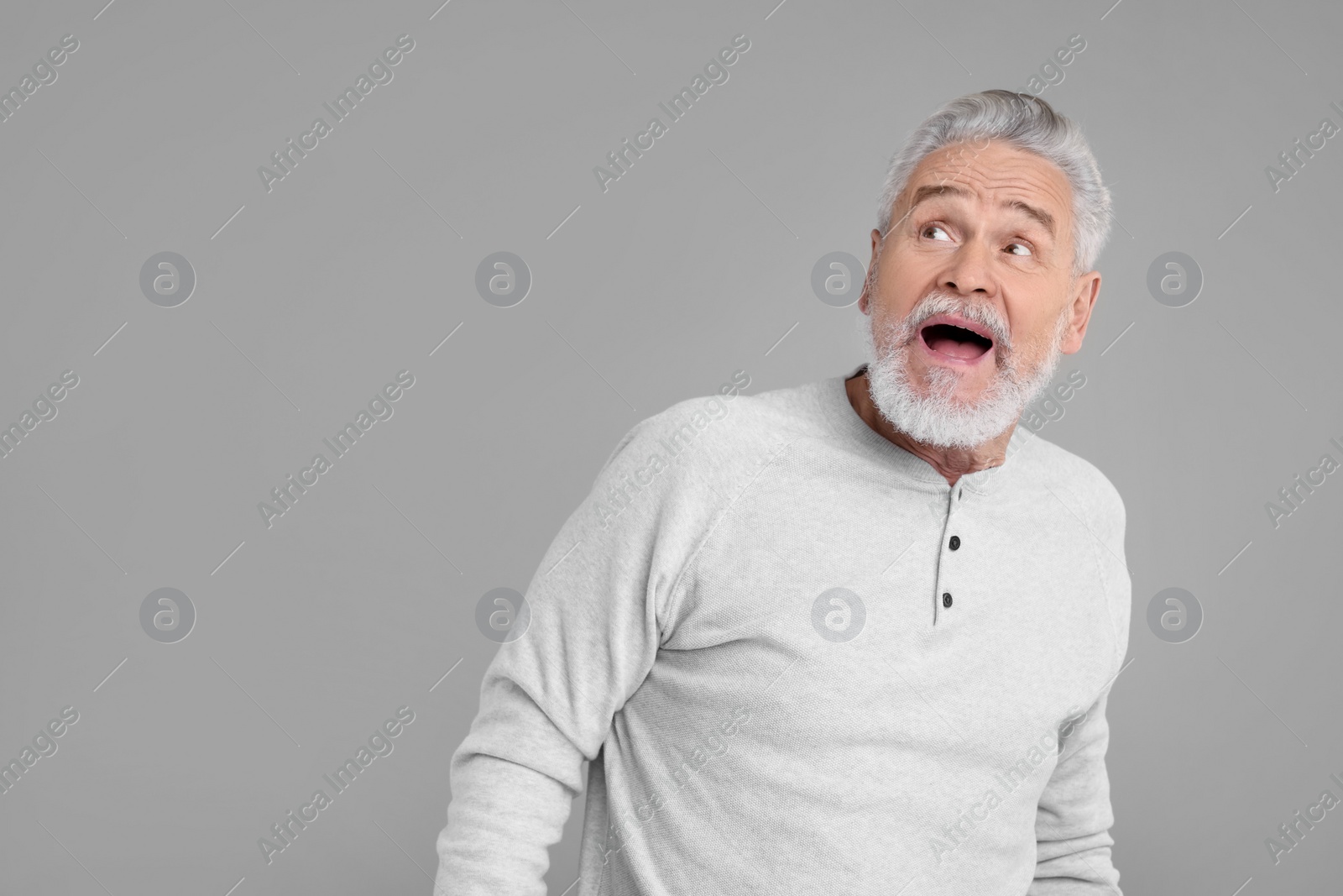 Photo of Portrait of surprised senior man on grey background, space for text