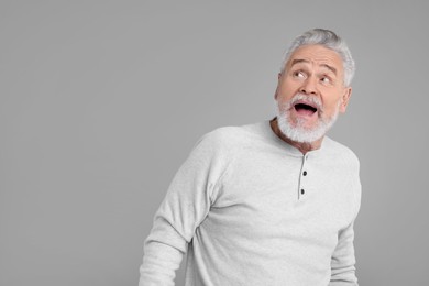Photo of Portrait of surprised senior man on grey background, space for text