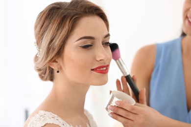 Photo of Makeup artist preparing bride before her wedding