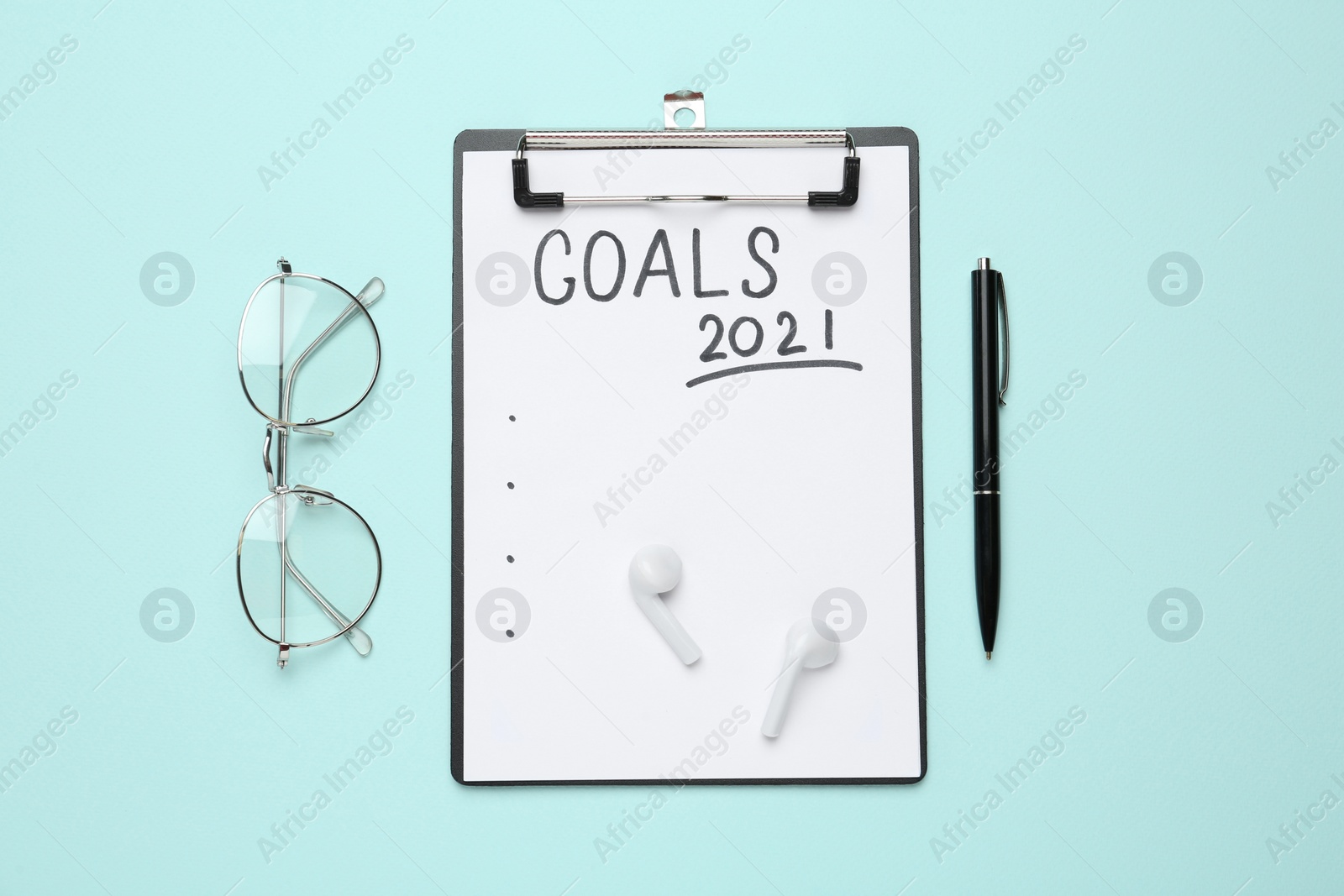 Photo of Clipboard with inscription Goals 2021, new year aims. Objects on turquoise background, flat lay