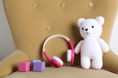 Photo of Baby songs. Toy bear, headphones and cubes on armchair