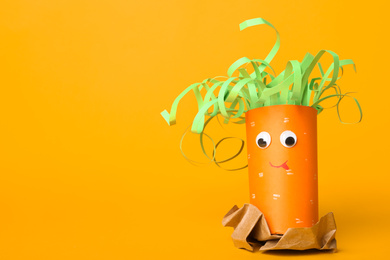 Photo of Toy carrot made of toilet paper hub on yellow background. Space for text
