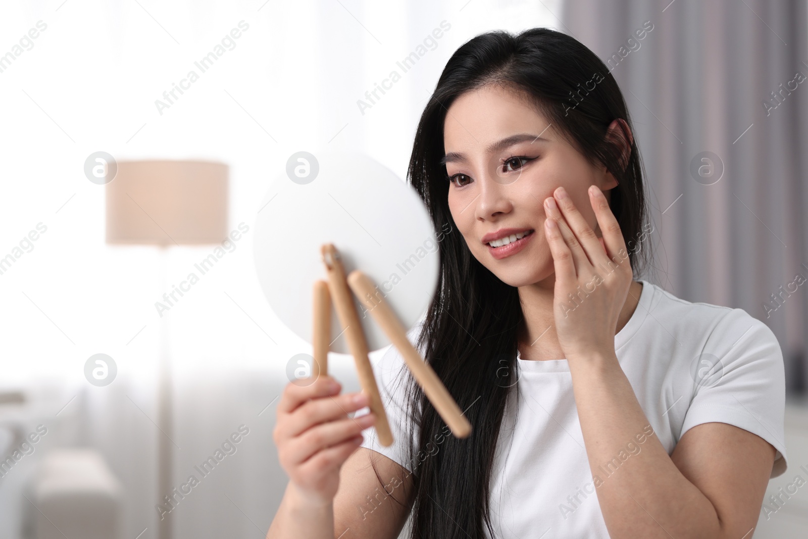 Photo of Woman with perfect skin looking at mirror indoors, space for text