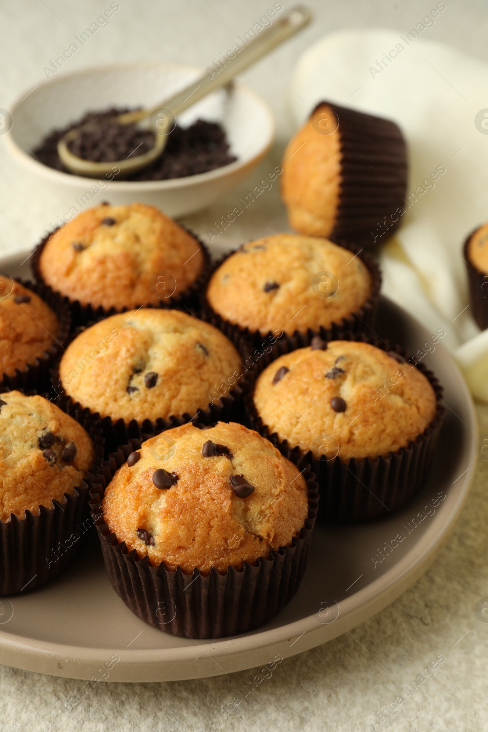 Photo of Delicious sweet muffins with chocolate chips on light textured table