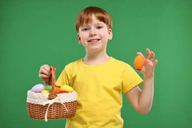 Easter celebration. Cute little boy with painted eggs on green background