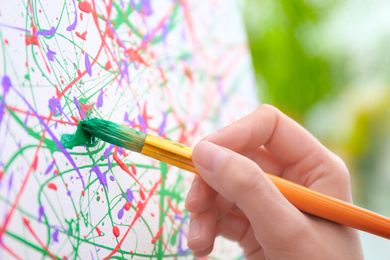 Photo of Artist painting on canvas with brush, closeup