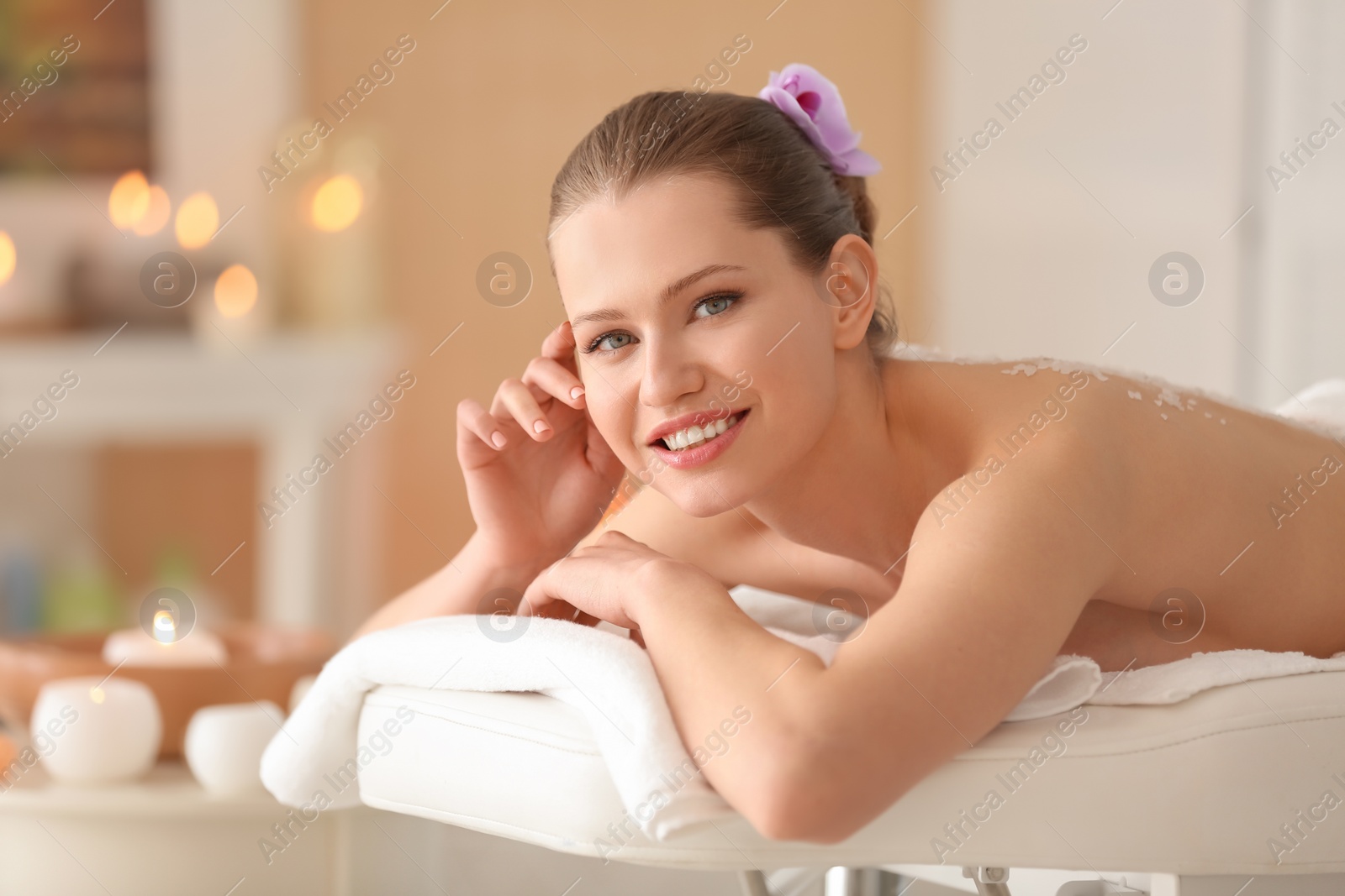 Photo of Beautiful young woman having massage with body scrub in spa salon