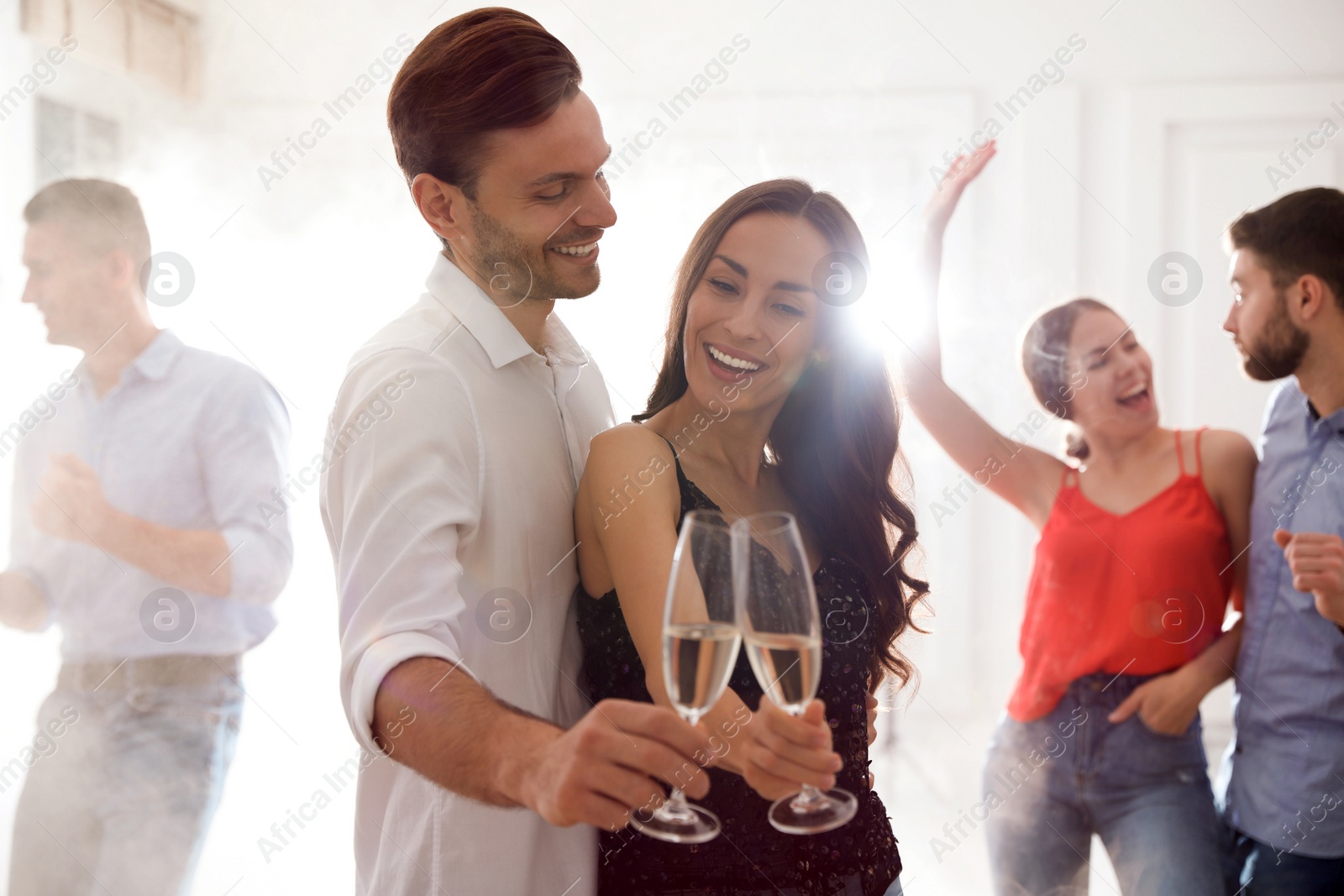 Photo of Lovely young couple with glasses of champagne at dancing party