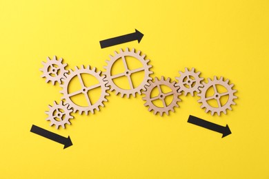 Photo of Business process organization and optimization. Scheme with wooden figures and arrows on yellow background, top view