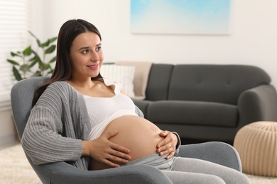 Photo of Beautiful pregnant woman sitting in armchair at home