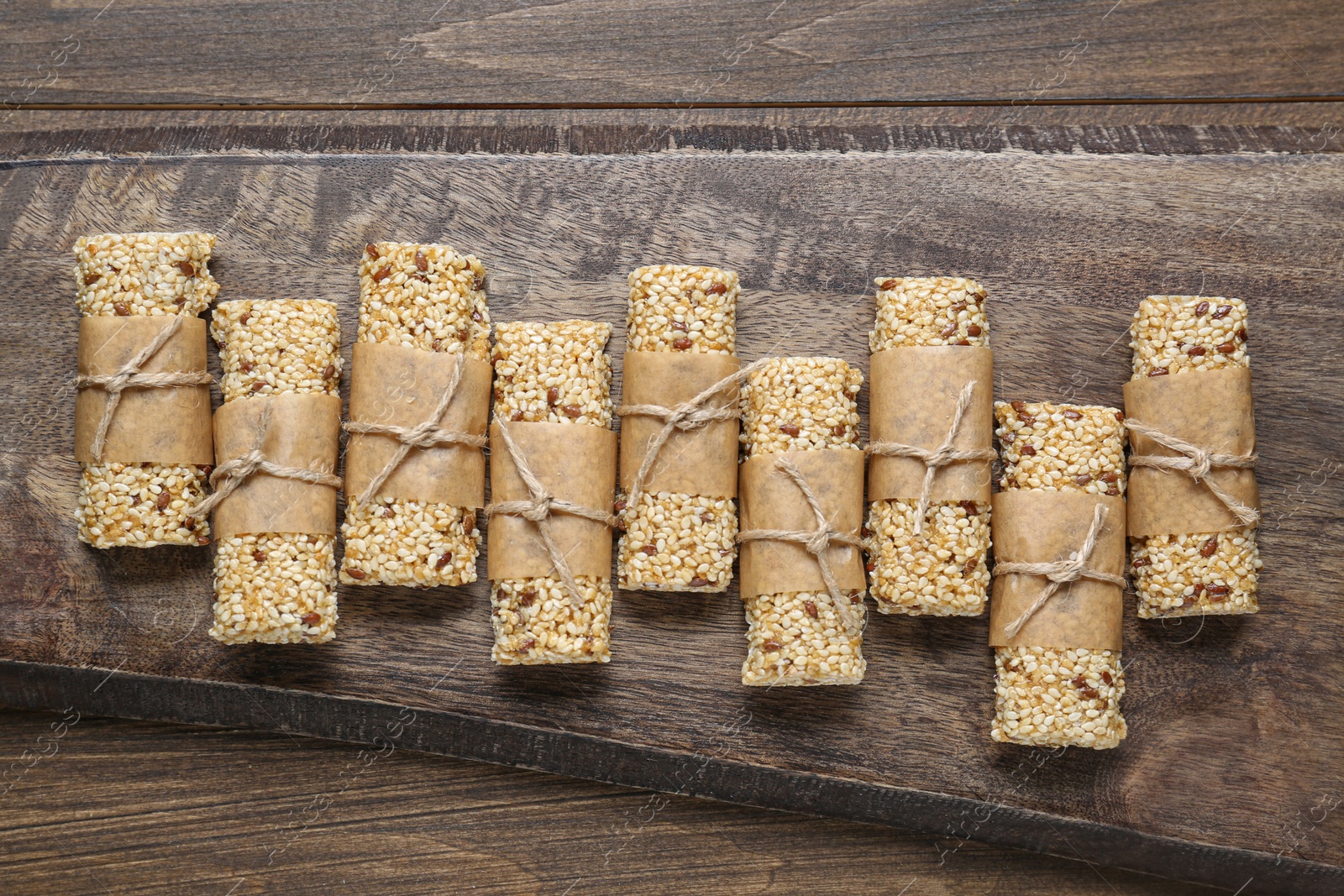 Photo of Tasty sesame seed bars on wooden table, top view