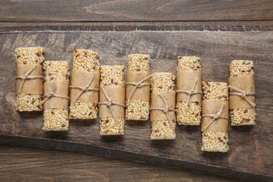 Photo of Tasty sesame seed bars on wooden table, top view