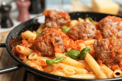 Photo of Pasta with meatballs and tomato sauce on frying pan, closeup