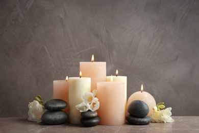 Photo of Beautiful composition with candles, stones and flowers on table against grey background