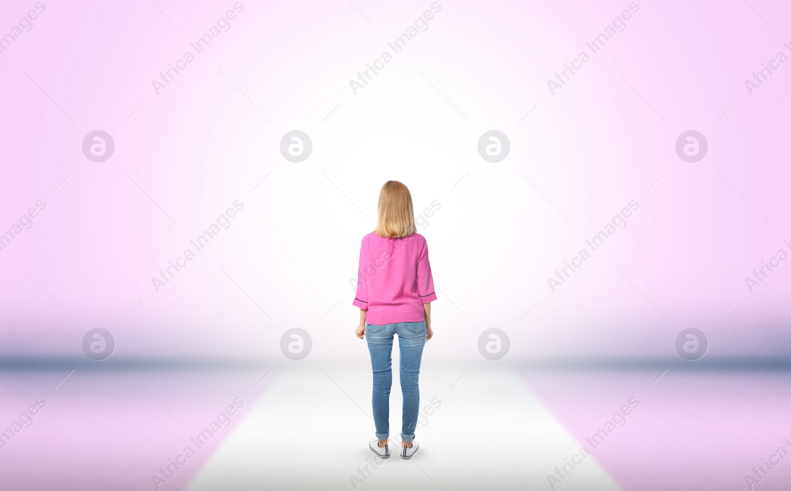 Image of Woman standing in front of pink wall, back view