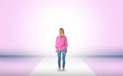Woman standing in front of pink wall, back view