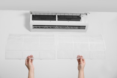 Photo of Woman holding air conditioner filters indoors, closeup
