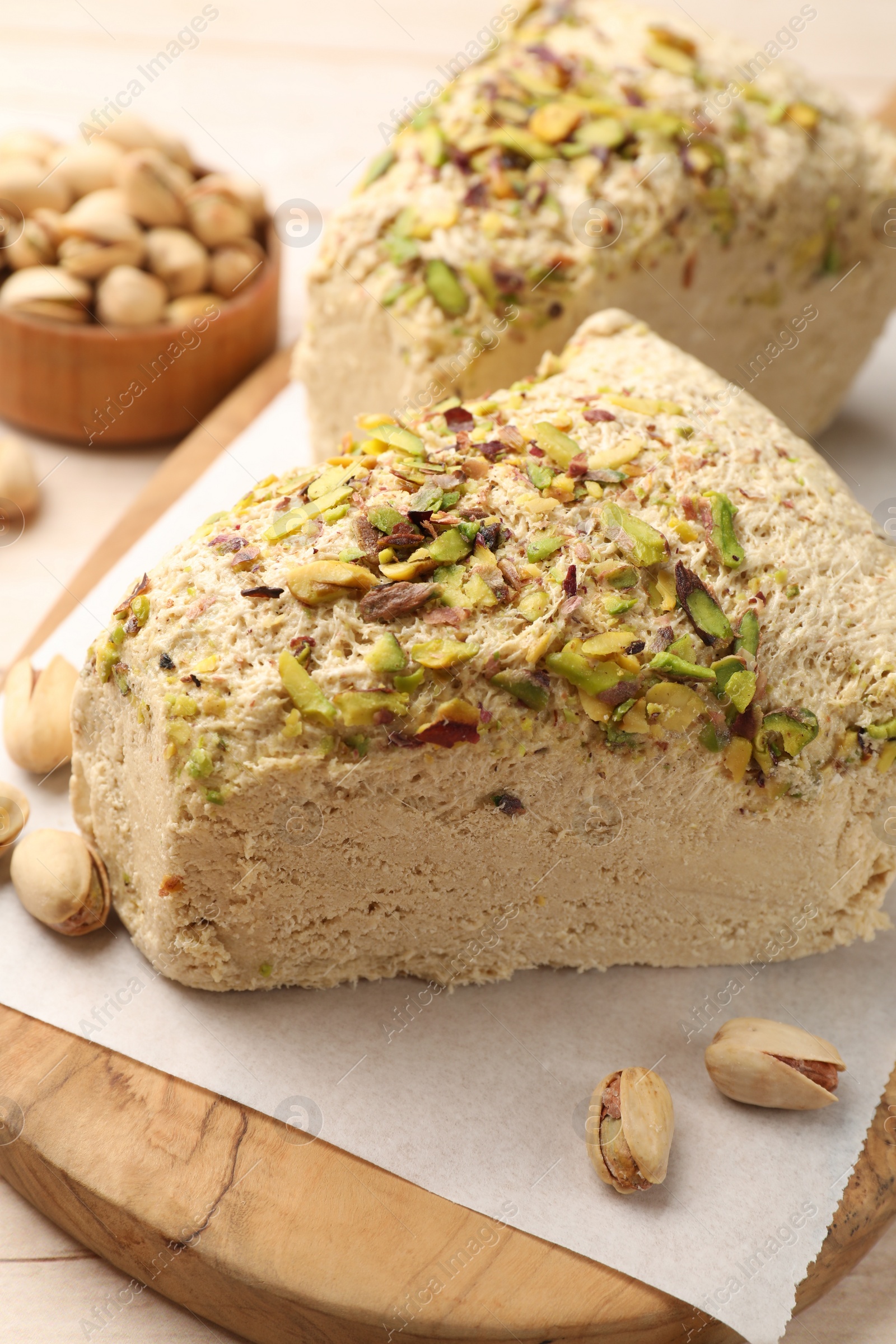 Photo of Tasty halva with pistachios on table, closeup