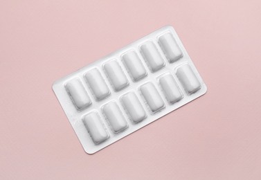 Photo of Blister with chewing gums on pink background, top view