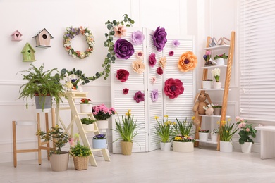Photo of Easter photo zone with plants and paper flowers indoors