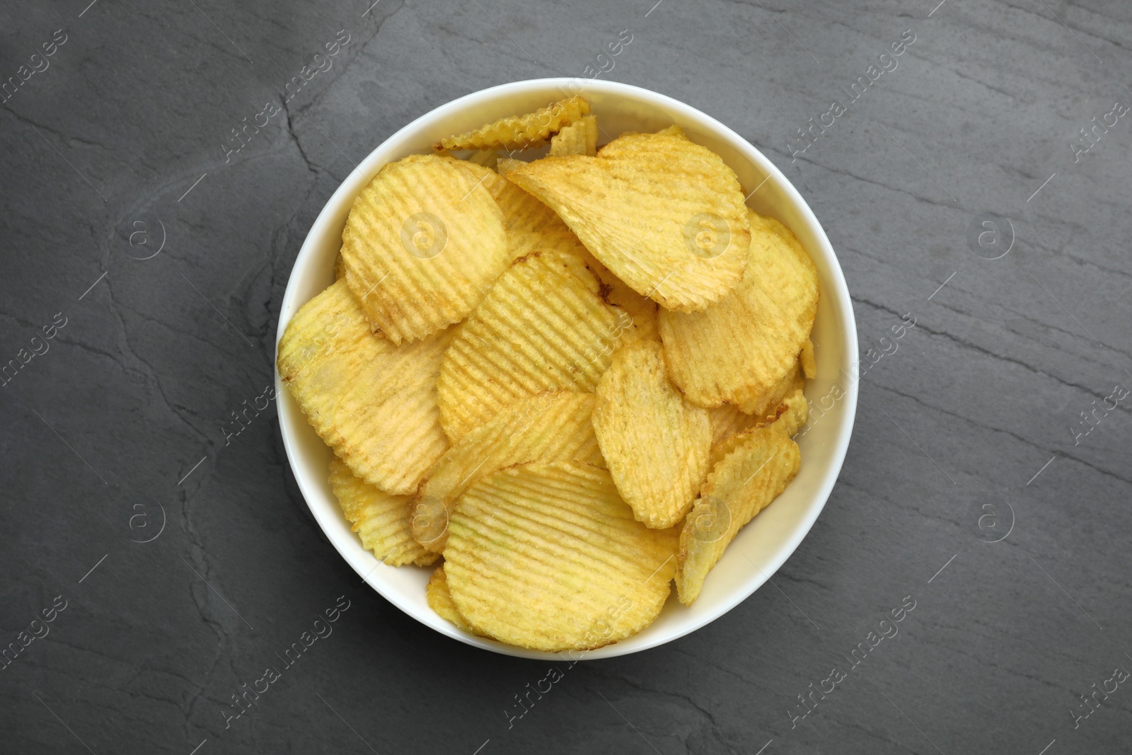 Photo of Bowl of potato chips on grey table, top view