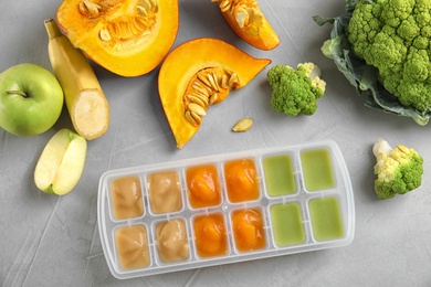 Photo of Flat lay composition with ice cube tray of baby food on gray background