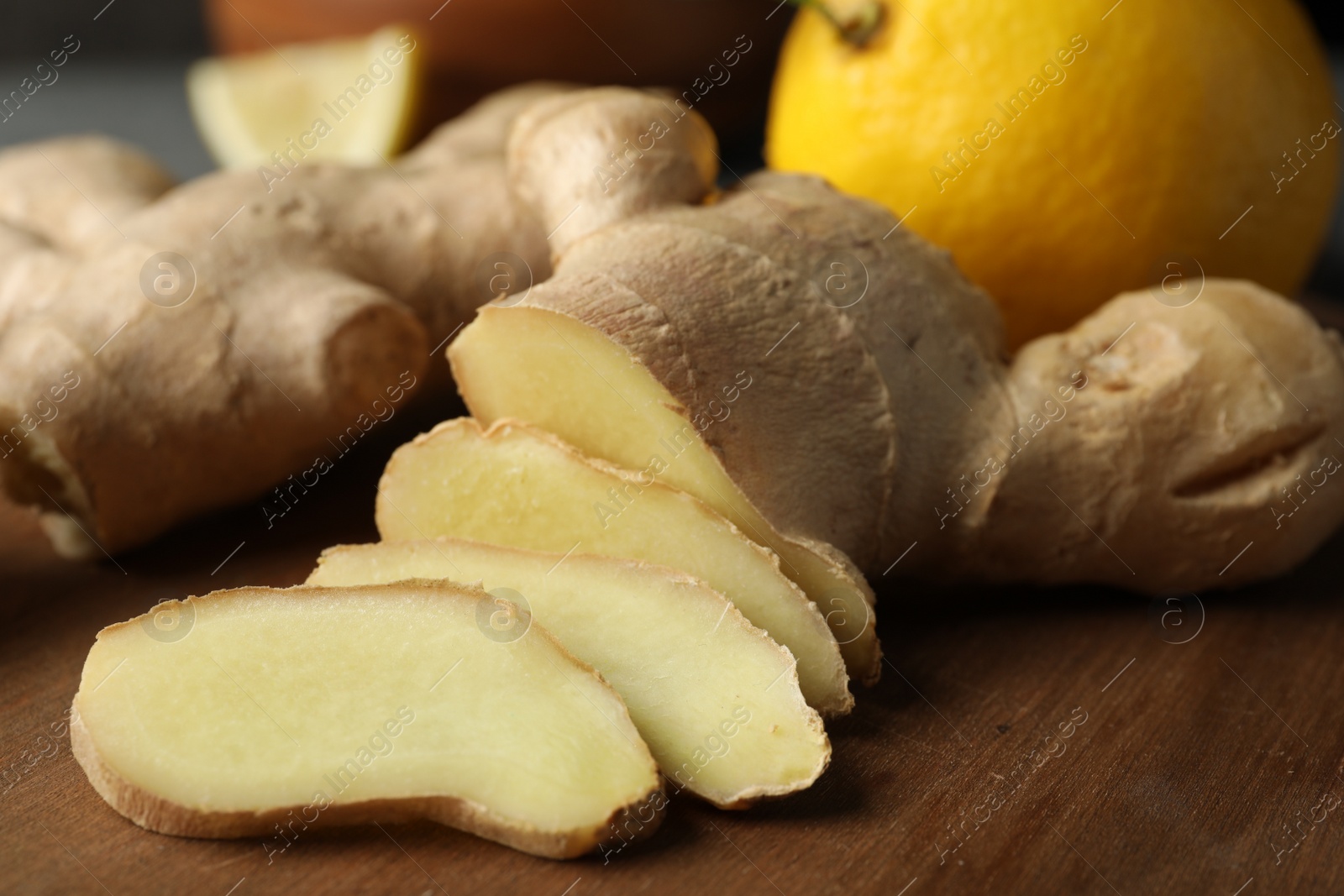 Photo of Cut ginger and lemon on wooden board, closeup