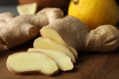 Photo of Cut ginger and lemon on wooden board, closeup