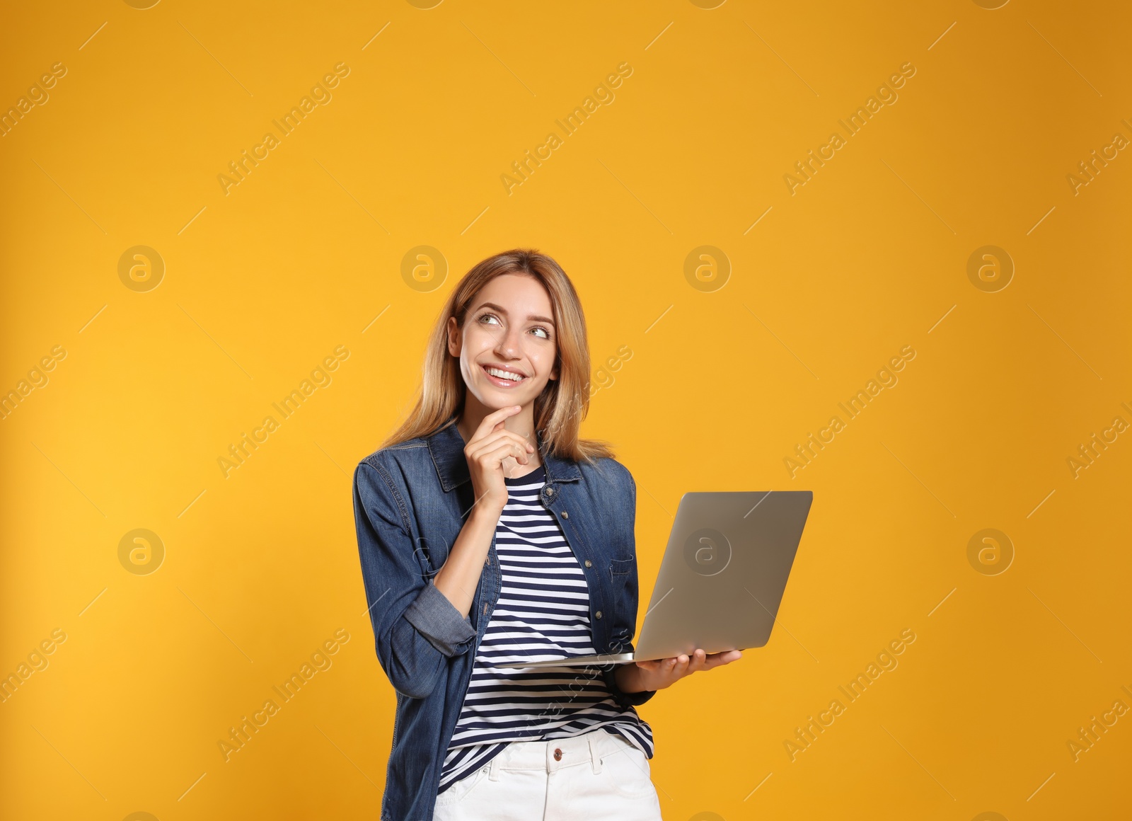 Photo of Portrait of woman with modern laptop on yellow background