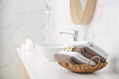 Photo of Basket with clean towels on counter in bathroom. Space for text