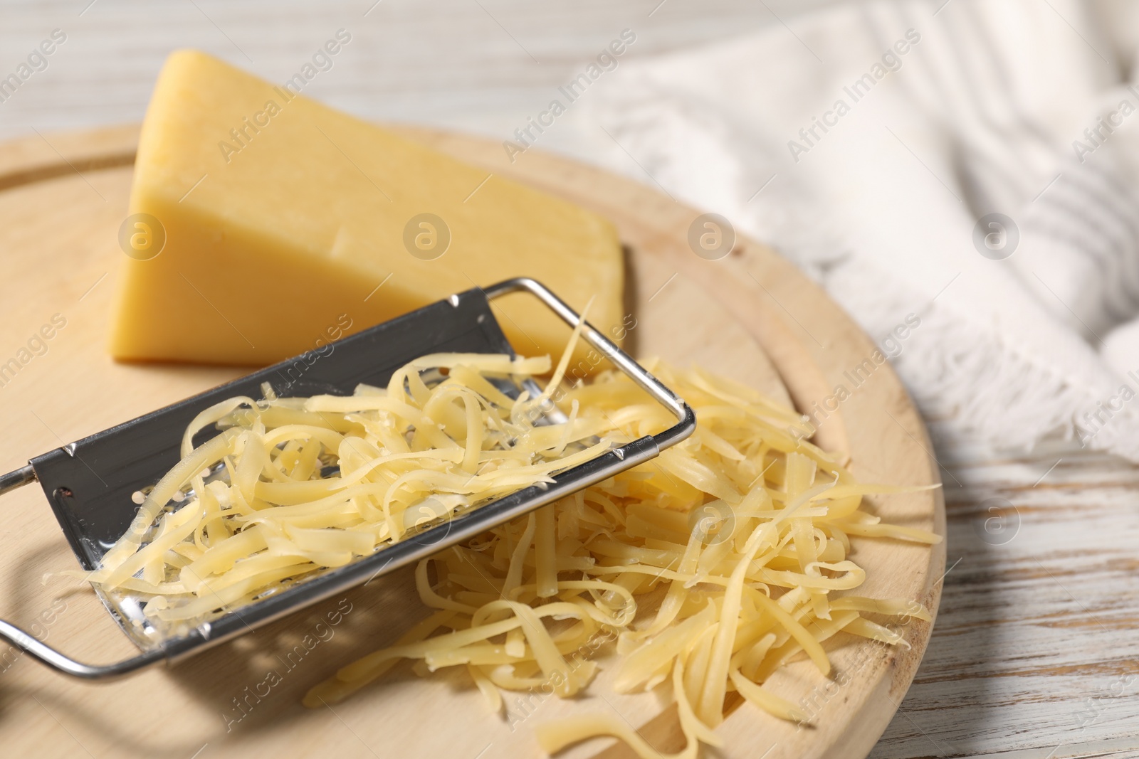 Photo of Grated, whole piece of cheese and grater on wooden rustic table, closeup