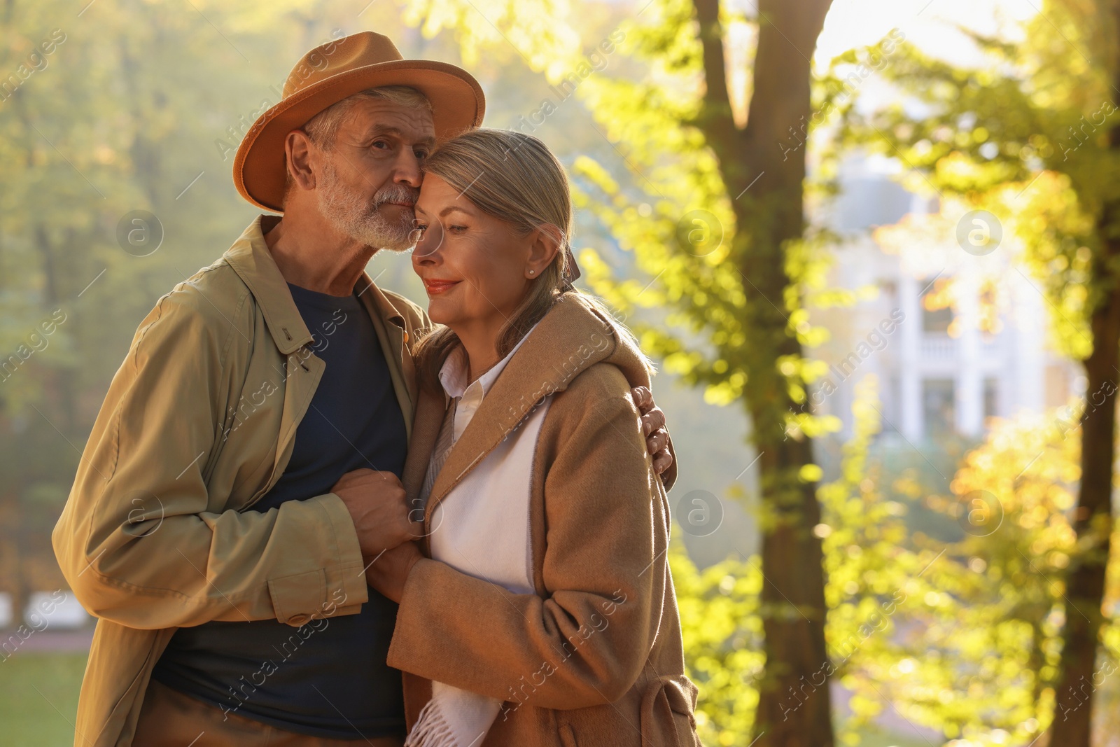 Photo of Affectionate senior couple in autumn park, space for text