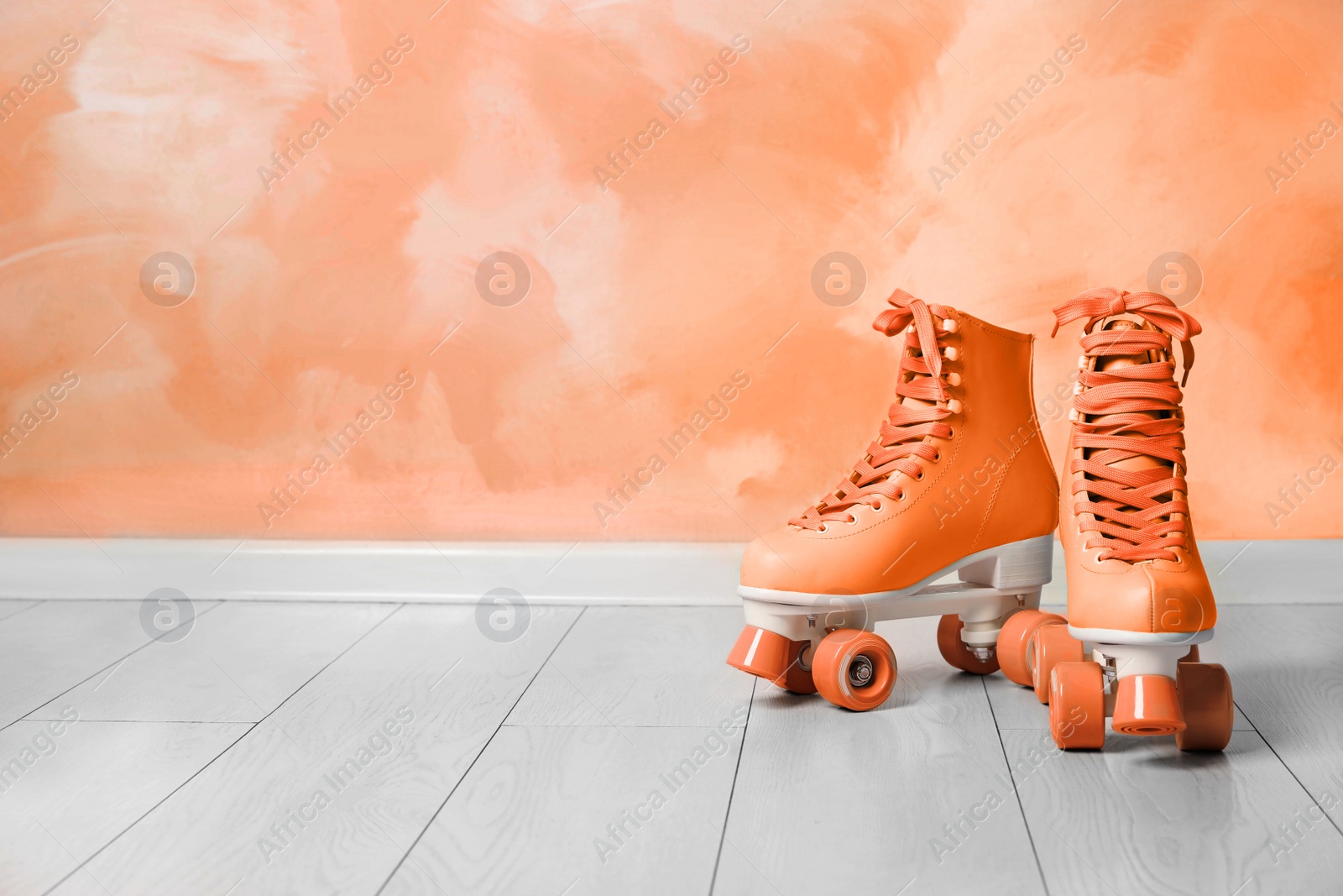 Image of Vintage roller skates on floor near orange wall. Space for text