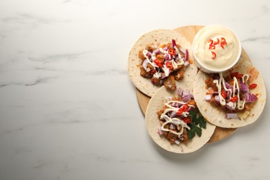 Photo of Delicious tacos with vegetables, meat and sauce on white marble table, top view. Space for text