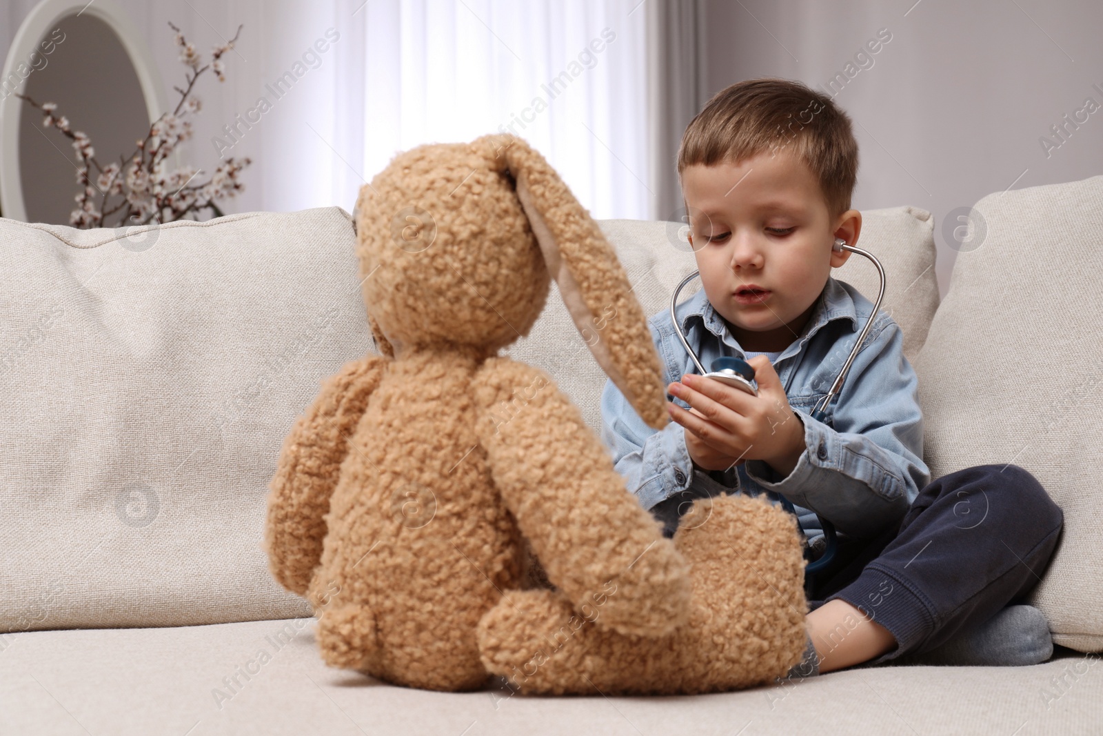 Photo of Cute little boy playing with stethoscope and toy bunny at home. Future pediatrician