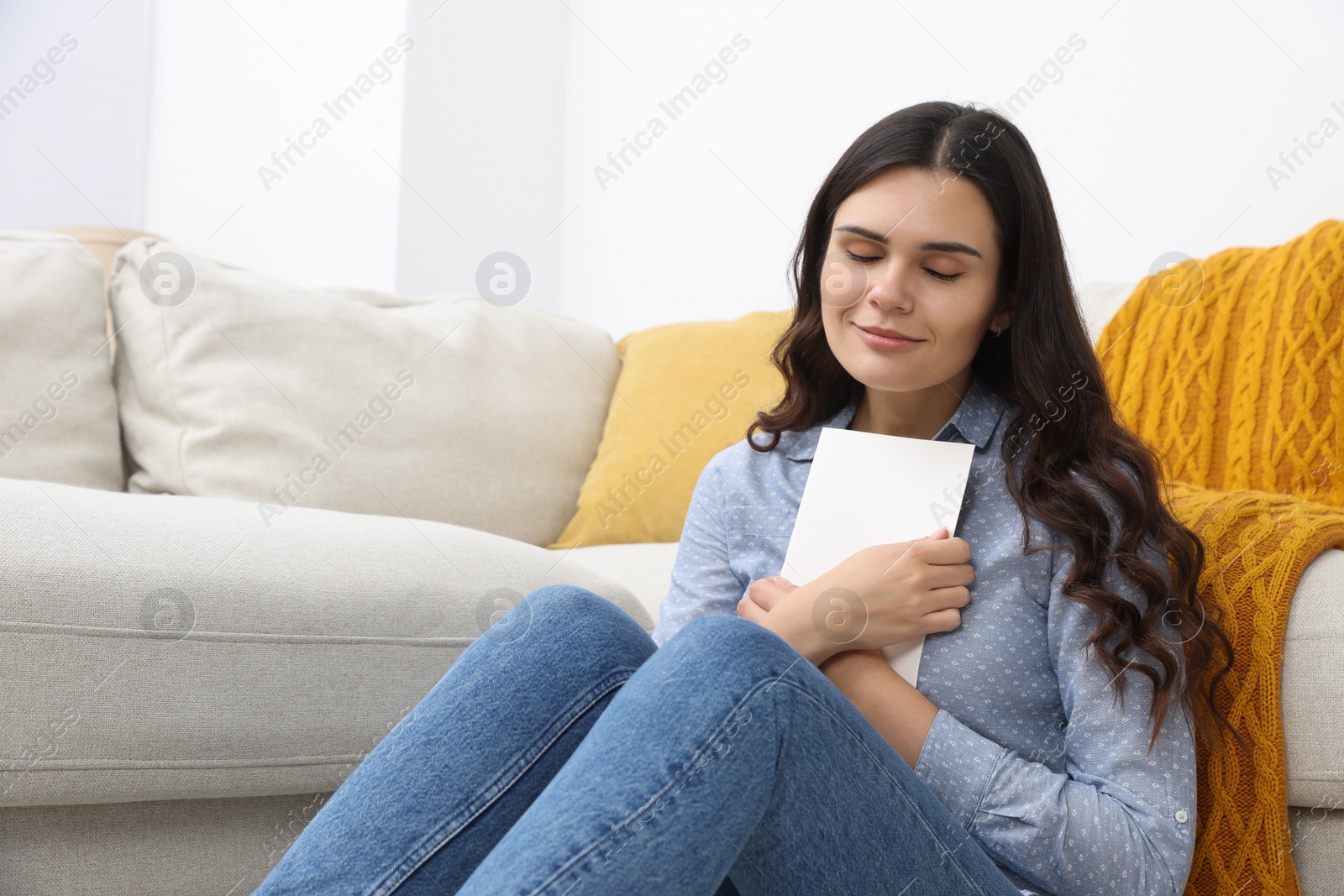 Photo of Young woman with greeting card on floor in living room, space for text