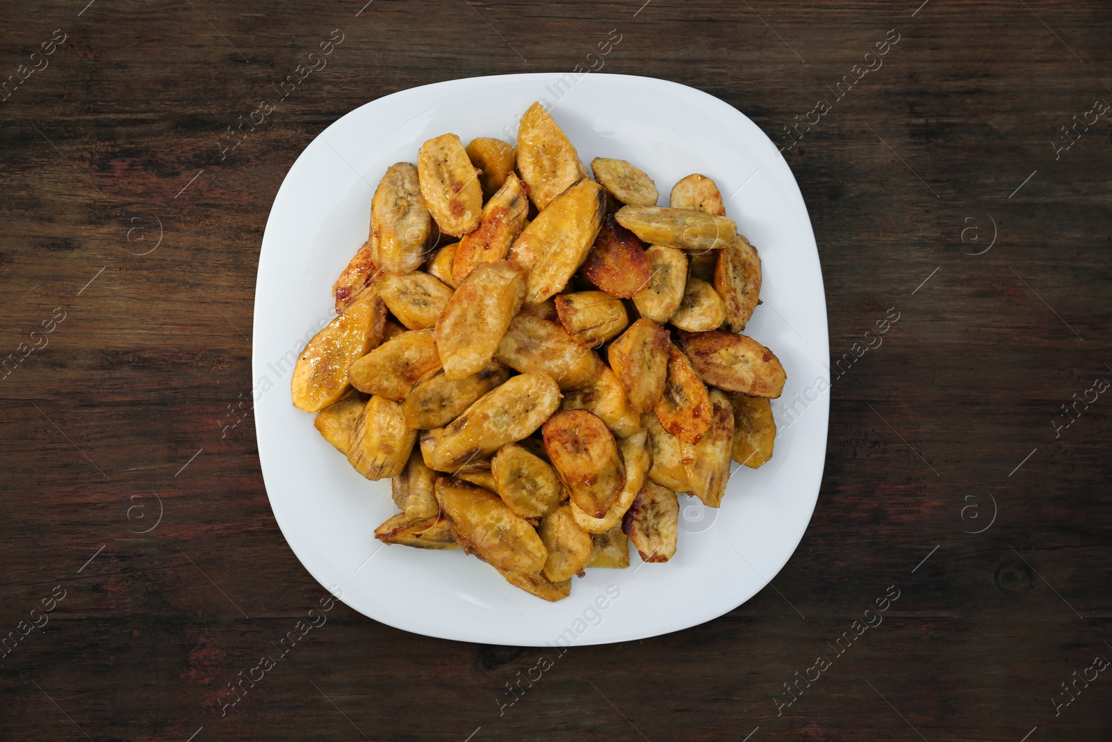 Photo of Tasty deep fried banana slices on wooden table, top view