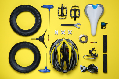 Photo of Set of different bicycle tools and parts on yellow background, flat lay