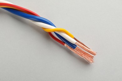 Photo of Many twisted electrical wires on light background, closeup
