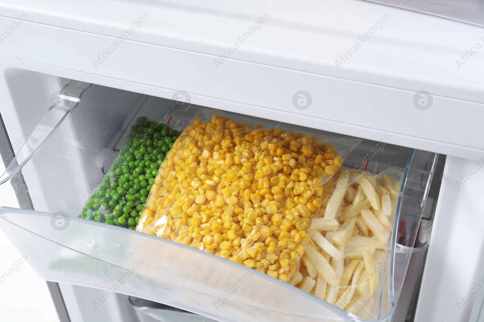 Photo of Plastic bags with frozen vegetables in refrigerator, closeup